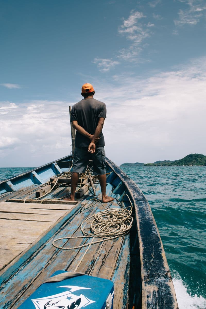 Man standing on a boat looking toward the horizon
